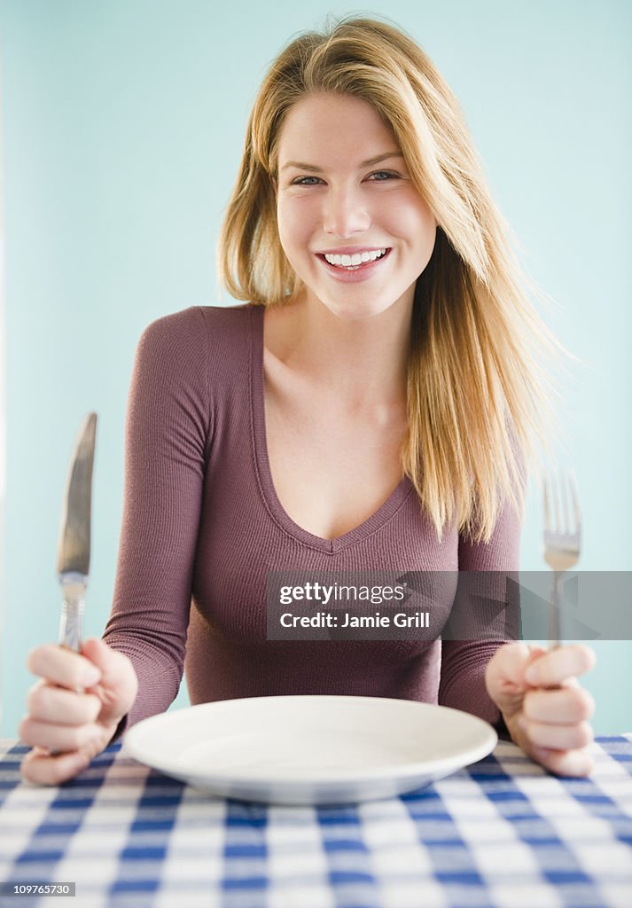 Young woman holding knife and fork