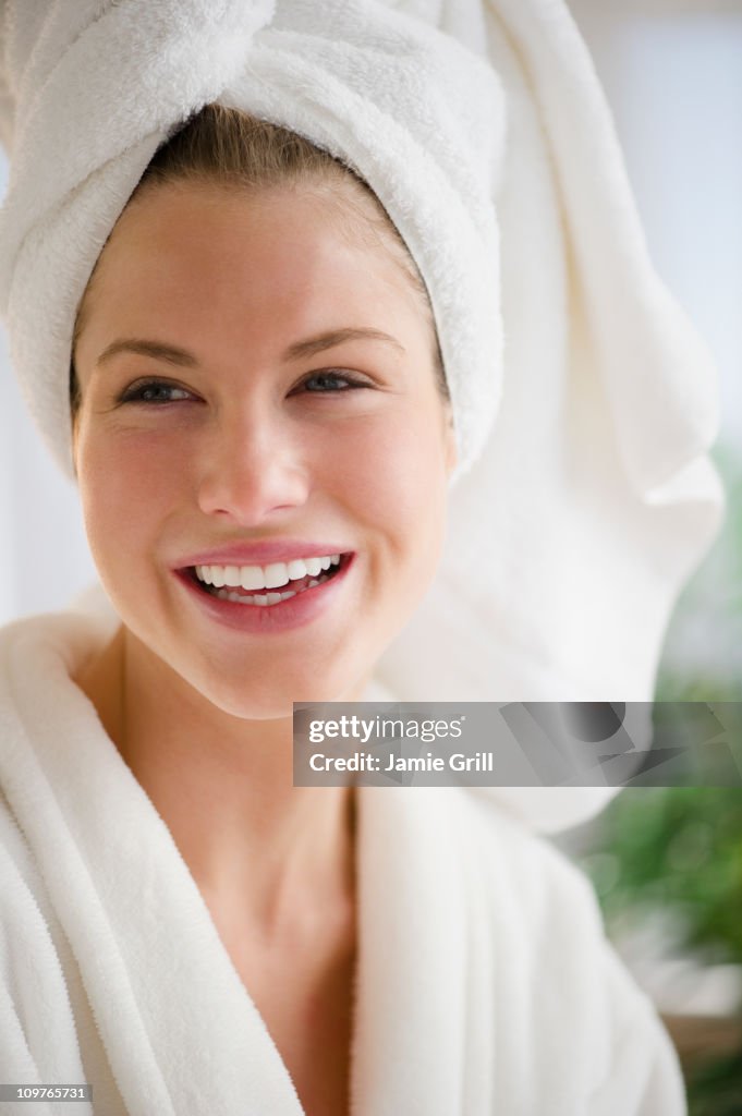 Woman in robe with hair wrapped in towel, smiling