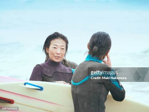 Women are having fun at a beach with a surfboard