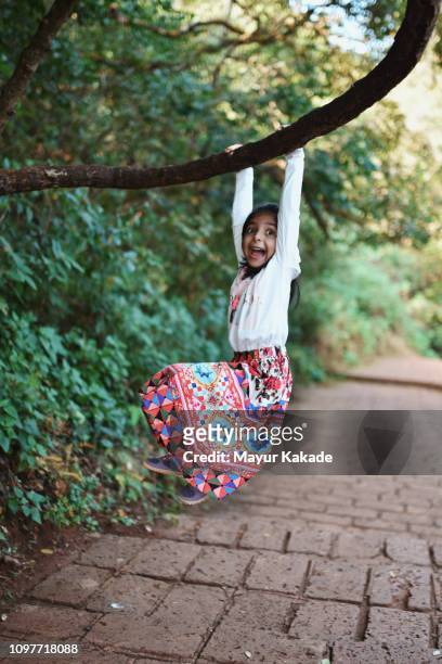 Young girl (4-5 years) hanging to the tree trunk