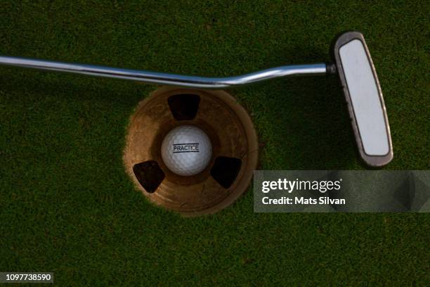 putting green with hole and golf putter and golf ball - hole in one fotografías e imágenes de stock