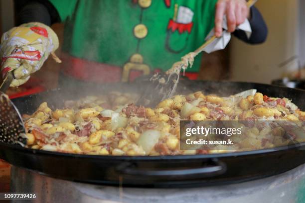 man preparing potato dish at market stall. - prague christmas stock-fotos und bilder