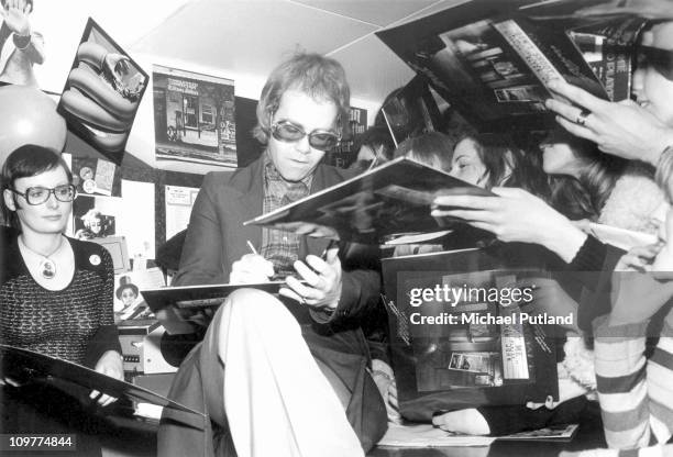 British singer Elton John signing copies of his record 'Don't Shoot Me I'm Only the Piano Player' at Noel Edmond's Record Bar in the King's Road,...