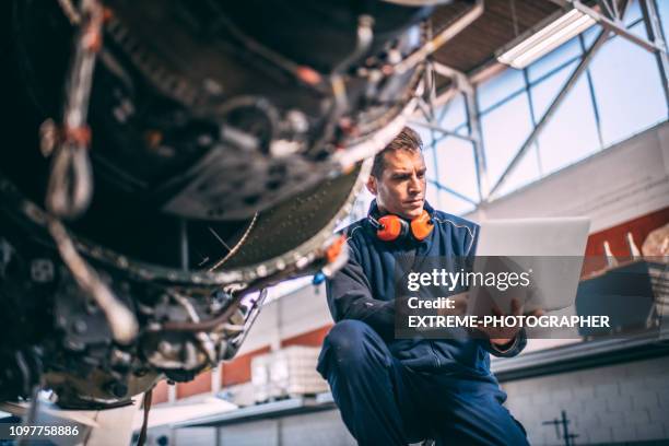 mecánico de aviones usando un ordenador portátil de reparación y mantenimiento de un motor de jet en un hangar de mantenimiento - hangar fotografías e imágenes de stock