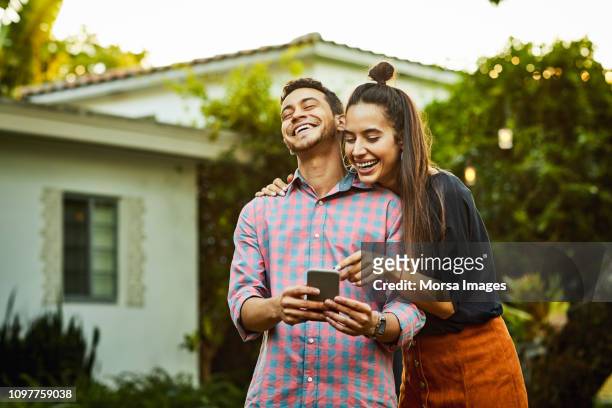happy couple looking at smart phone in back yard - happy couple stock pictures, royalty-free photos & images