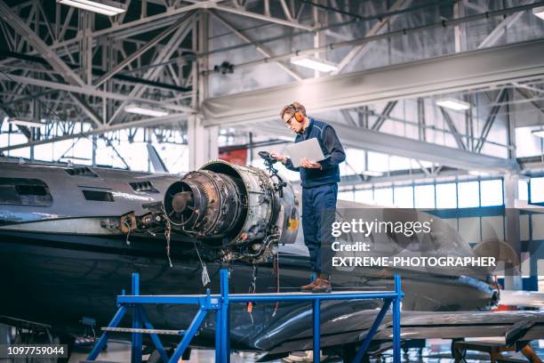 aircraft engineer standing on a raised work platform, looking at a display of a probe inspection camera, trying to diagnose a fault in a jet engine of a small private airplane in a maintenance hangar - aeroplane engineer stock pictures, royalty-free photos & images