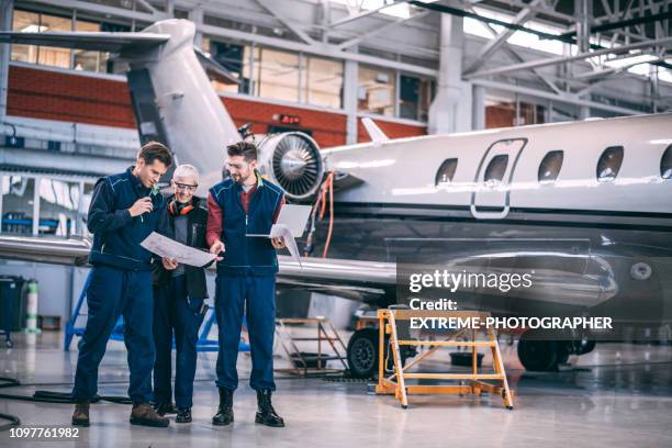 flugzeug mechaniker crew zusammen in einen flugzeughangar zu koordinieren - flugzeugmechaniker stock-fotos und bilder