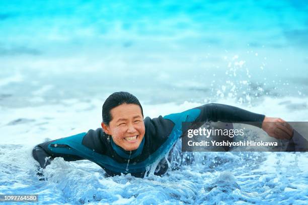 surfer paddling with surfboard on japanese beach in splash. - puddling stockfoto's en -beelden