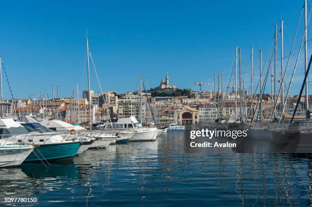 The Vieux Port with boats in Marseille, France with the Notre-Dame de la Garde , a Catholic basilica in the background.