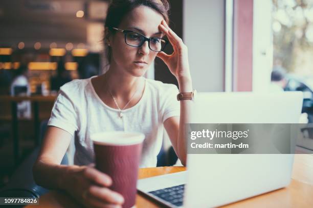 femme d’affaires grave au café lecture des nouvelles en ligne dans la politique - shock stock photos et images de collection