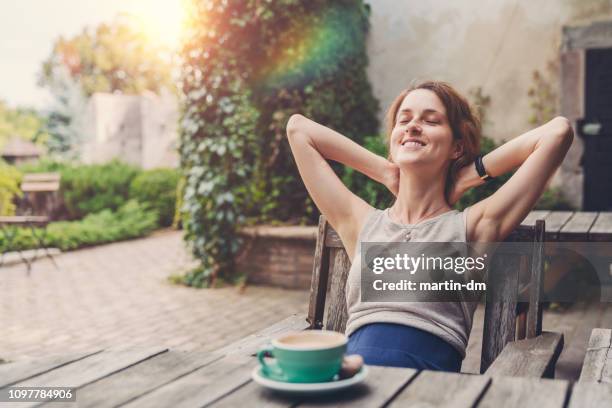 femme décontractée, boire du café dans le jardin - happy woman in early morning sunlight photos et images de collection