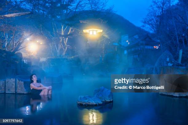 woman relaxing in a japanese hot spring at dawn. - thermal pool stock pictures, royalty-free photos & images