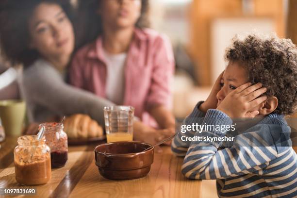 sad african american boy crying during breakfast time at dining table. - african dining stock pictures, royalty-free photos & images