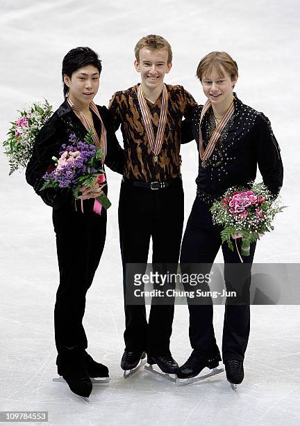 2nd place winner Keiji Tanaka of Japan, 1st place winner Andrei Rogozine of Canada and 3rd place winner Alexander Majorov of Sweden pose on the ice...