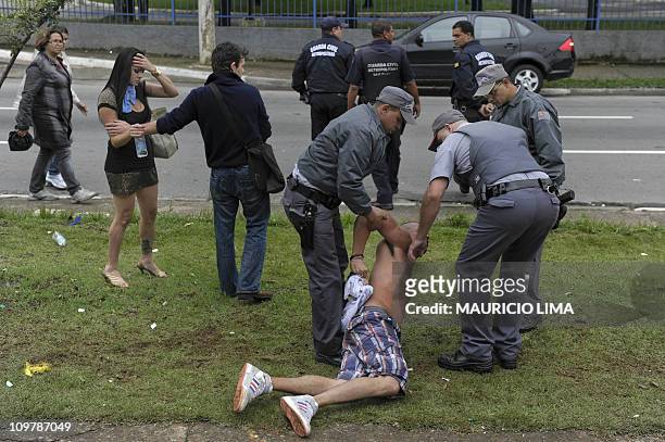 Drunk reveller is dragged handcuffed by militarized policemen after attemping to attack private security guards just outside a VIP area at the...