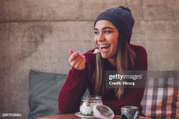 glückliche frau essen gesunden süßen snack - women yogurt stock-fotos und bilder