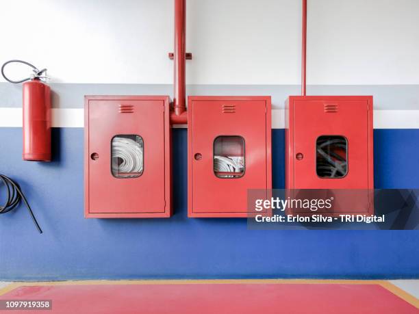 fire safety in the security area with hose fittings and fire extinguishers attached to the wall - brandslang stockfoto's en -beelden