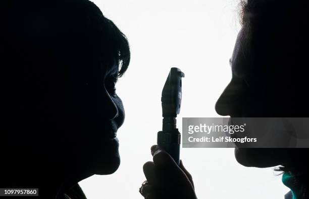 Close-up of an undentified patient as she looks to one side while a doctor uses a ophthalmoscope to look into her eye during an exam at the College...