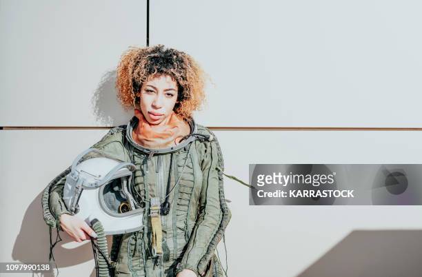 beautiful woman poses looking at camera dressed as an astronaut - astronaut portrait stock-fotos und bilder