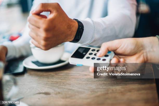 man at cafe paying contactless with smartwatch - smartwatch pay stock pictures, royalty-free photos & images