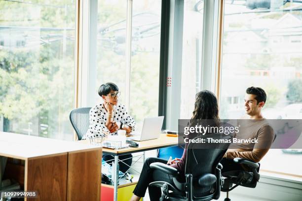 creative team in discussion while seated at workstation in design studio - modern design studio stock pictures, royalty-free photos & images