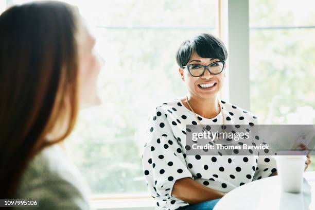 smiling mature businesswoman in discussion with colleague in office conference room - colleagues in discussion in office conference room fotografías e imágenes de stock