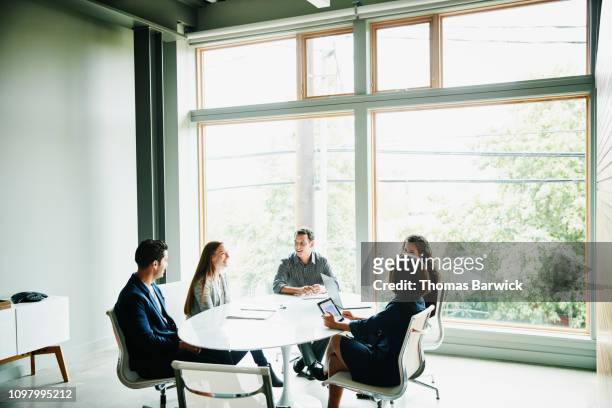 smiling colleagues discussing project during meeting in office conference room - five people meeting stock pictures, royalty-free photos & images
