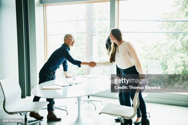 businesswoman shaking hands with client before meeting in office conference room - customer relationship management stockfoto's en -beelden