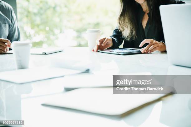 detail view of businesswoman working on digital tablet during meeting in office conference room - アクセス ストックフォトと画像