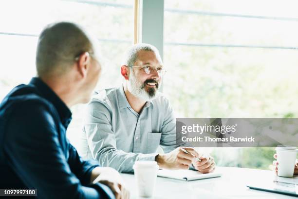 smiling mature businessman in discussion during meeting in office conference room - wisdom knowledge modern stockfoto's en -beelden