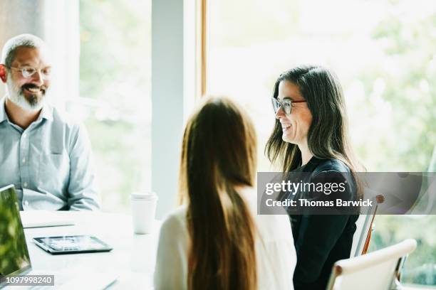 smiling mature businesswoman leading team meeting in office conference room - challenge authority stock pictures, royalty-free photos & images