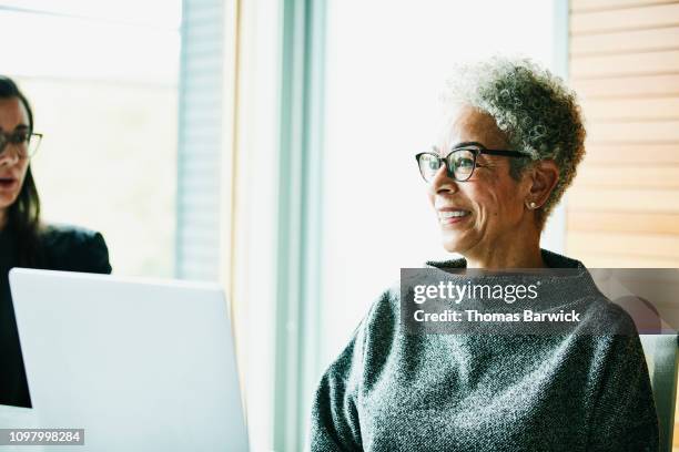 portrait of smiling senior businesswoman in meeting in office conference room - diverse mature women stock pictures, royalty-free photos & images