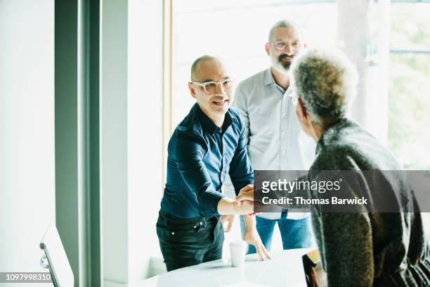mature businessman shaking hands with client before meeting in office conference room - primeira etapa fotografías e imágenes de stock
