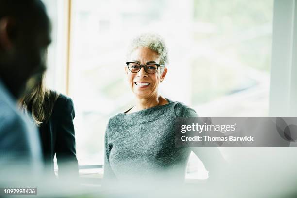 portrait of smiling senior businesswoman in discussion with coworkers - altmodern stock-fotos und bilder