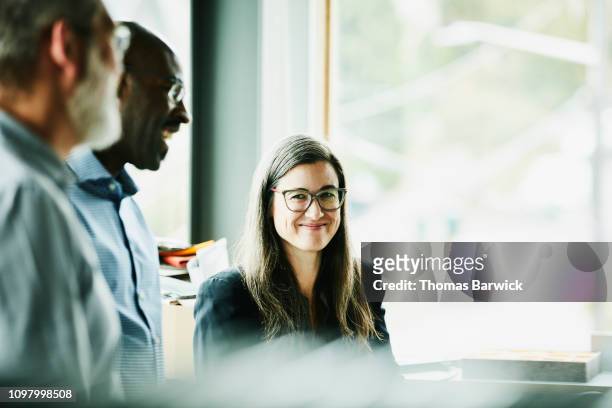 portrait of smiling mature businesswoman in discussion with coworkers in office - work place real talking stock pictures, royalty-free photos & images