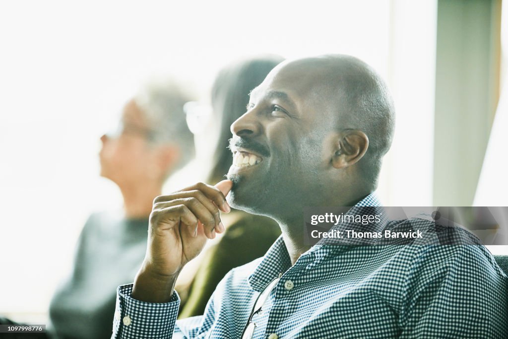 Portrait of smiling mature businessman listening during meeting with coworkers
