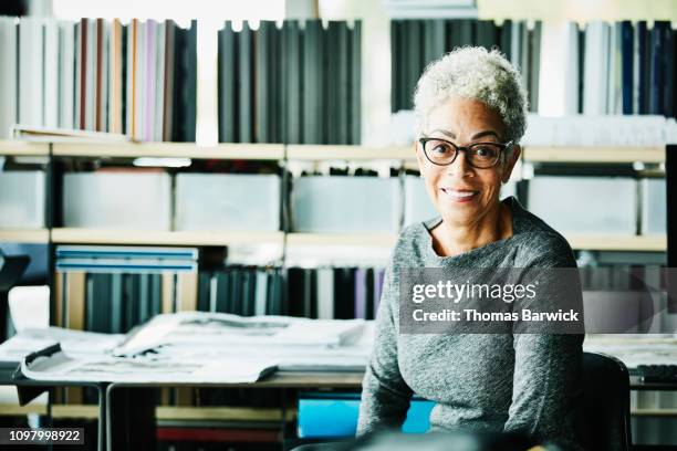 portrait of smiling senior businesswoman seated at workstation in design studio - african map stockfoto's en -beelden