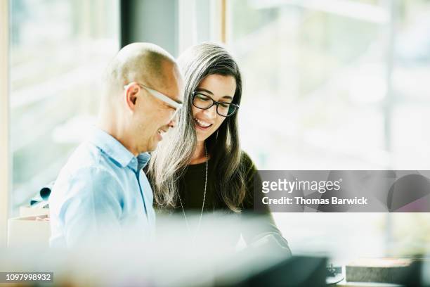 smiling coworkers looking at data on digital tablet in office - brainstorming stock photos et images de collection