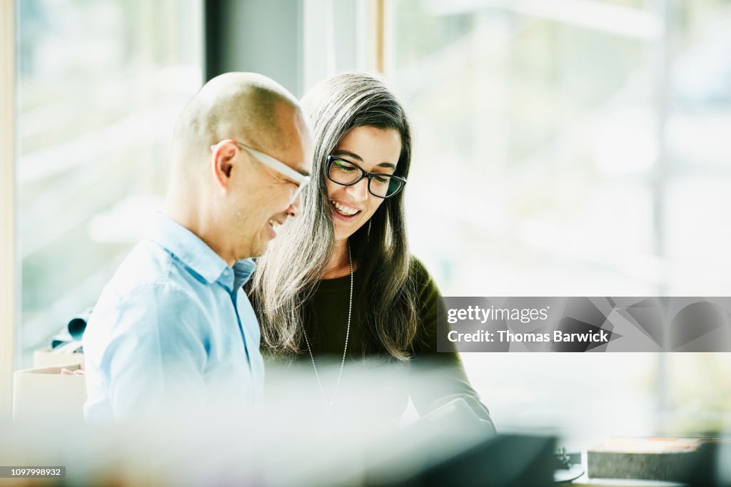 Smiling coworkers looking at data on digital tablet in office