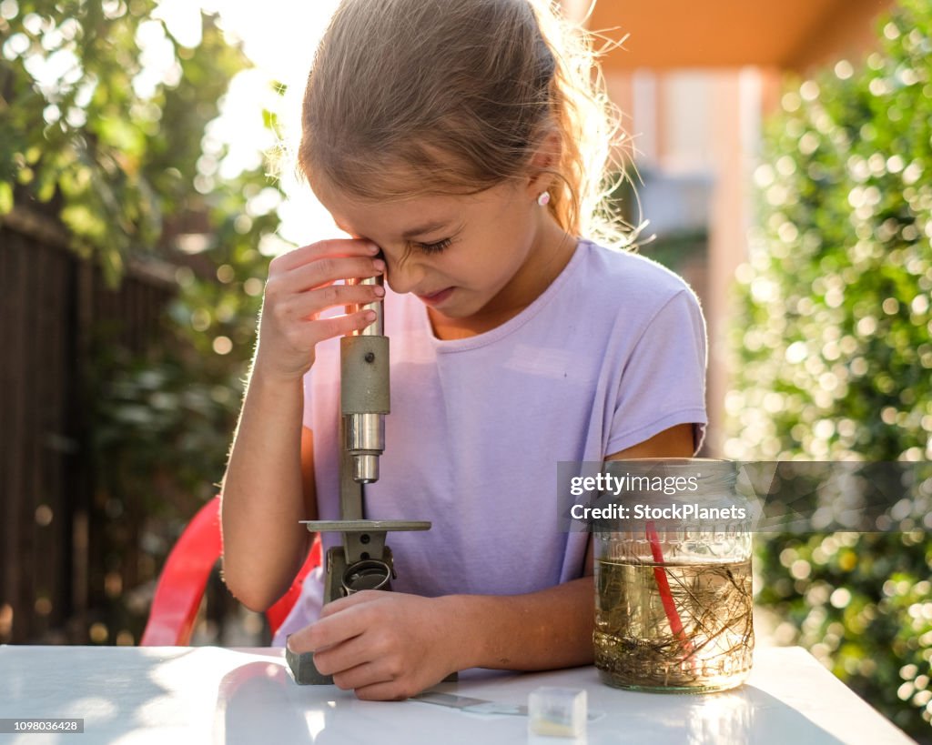 Cute little girl looking through the microscope