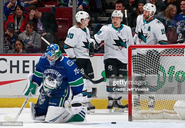 Michael Dipietro of the Vancouver Canucks looks on dejected as Kevin Labanc of the San Jose Sharks is congratulated by teammates Joe Thornton and...