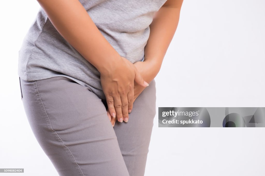 Young woman having painful stomachache with hands holding pressing her crotch lower abdomen. Medical or gynecological problems, healthcare concept