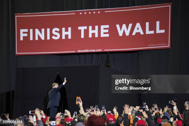 President Donald Trump waves as he stands in front of a banner reading "Finish the Wall" during a rally in El Paso, Texas, U.S., on Monday, Feb. 11,...