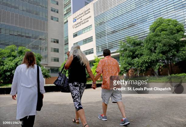 Dean DeMoe, right, and his wife, Deb DeMoe, center, of North Dakota, walk across the campus of Washington University School of Medicine on May 30...