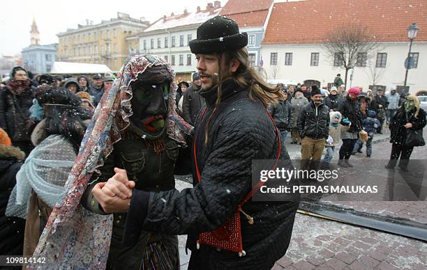 Revellers wearing masks and dressed as gypsies, horses, goats dance as they parade in the streets of the old town of Vilnius to celebrate Uzgavenes...