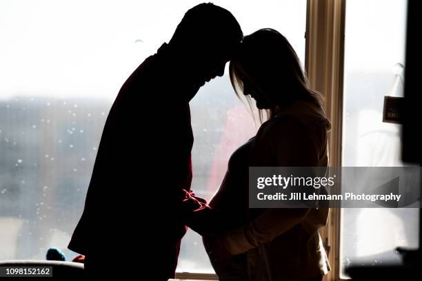 pregnant mother and father of twins in hospital room stand in silhouette shot - sibling hospital stock pictures, royalty-free photos & images