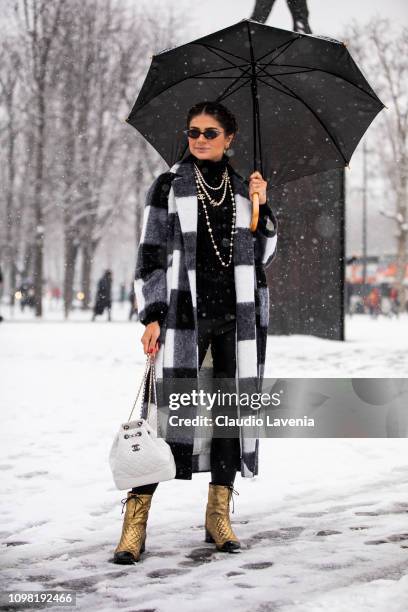Thassia Naves, wearing a black and white checked coat, gold Chanel boots and white Chanel bag, is seen outside Chanel show during Paris Fashion Week...