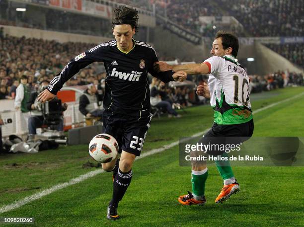 Mesut Ozil of Real Madrid fights for the ball with Pedro Munitis of Racing Santander during the La Liga match between Racing Santander and Real...