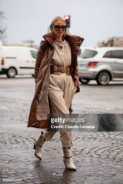 Leonie Hanne, wearing a beige jumpsuit, brown snake print leather belt, beige boots, Louis Vuitton bag and brown long jacket, is seen outside...