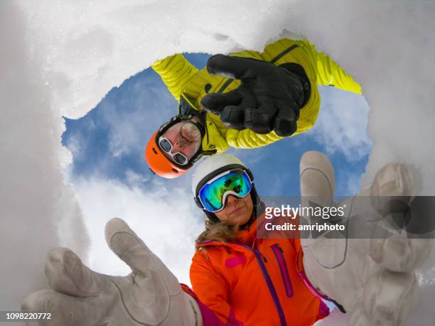 avalanche mountain rescue team reaching out helping hands in snow hole to save victim - sos stock pictures, royalty-free photos & images